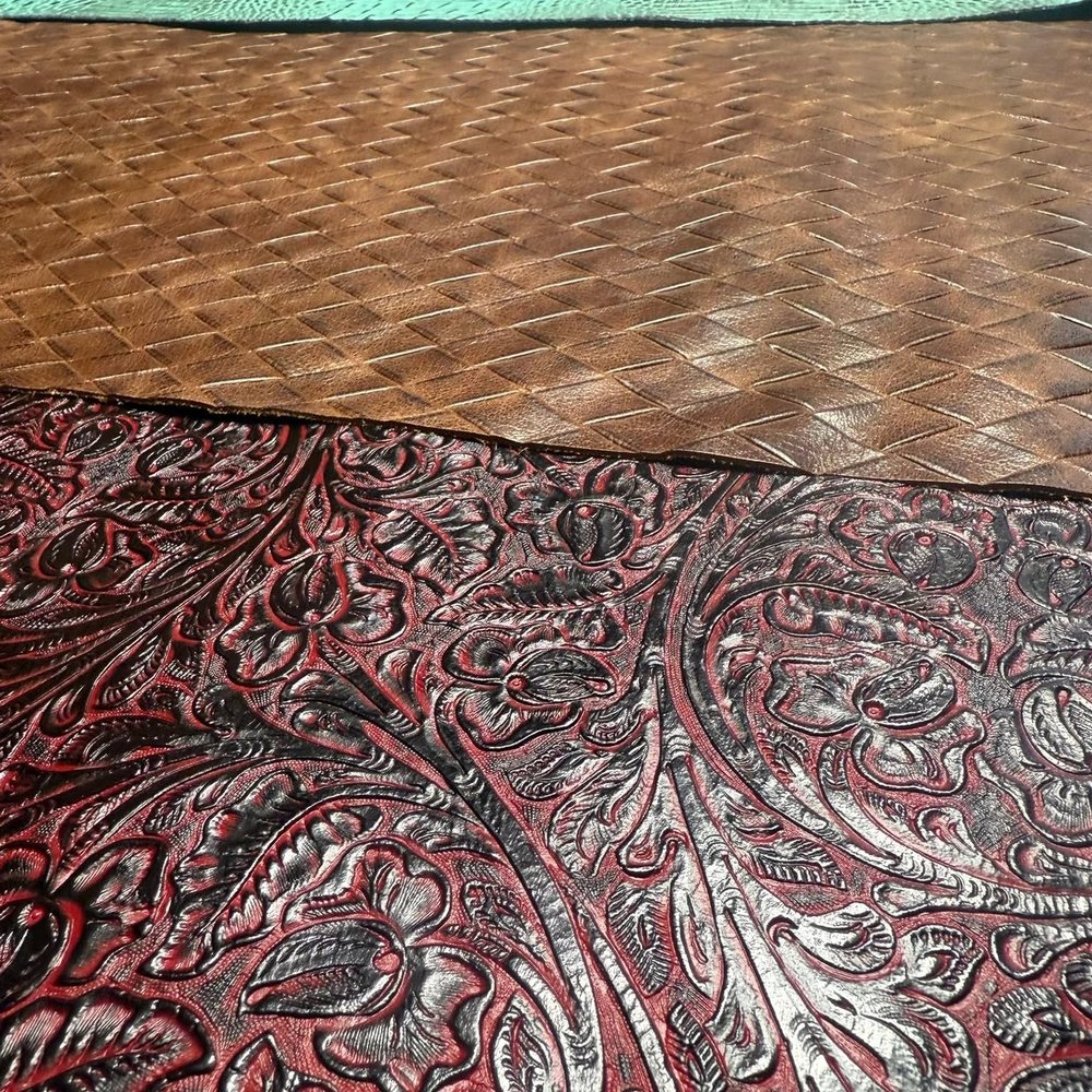 Close detail of hand-tooled leather: a basketweave field running into a carved floral border