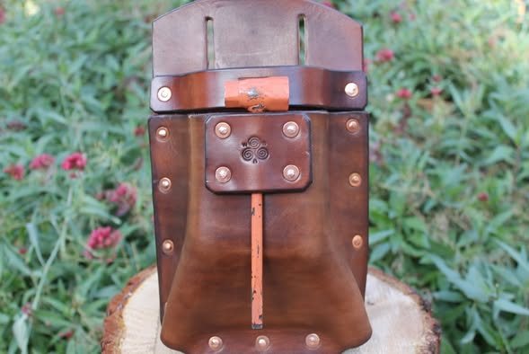 The wedge pouch closed and standing, with its rivet pattern and center stitch line visible